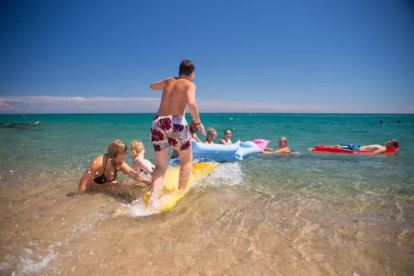 Jugendliche spielen im Wasser mit Luftmatratzen