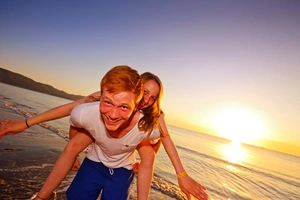 Zwei Freunde haben Spaß am Strand von Orbetello waehrend die Sonne untergeht