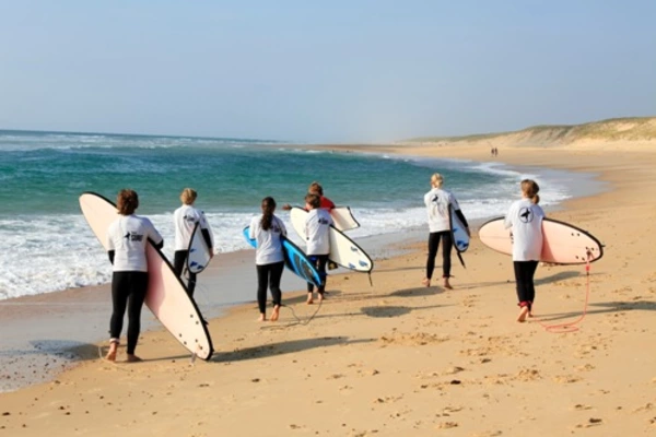 Die Jugendreise Teilnehmer des Surf Camps machen sich mit den Surfbrettern auf den Weg zum Meer